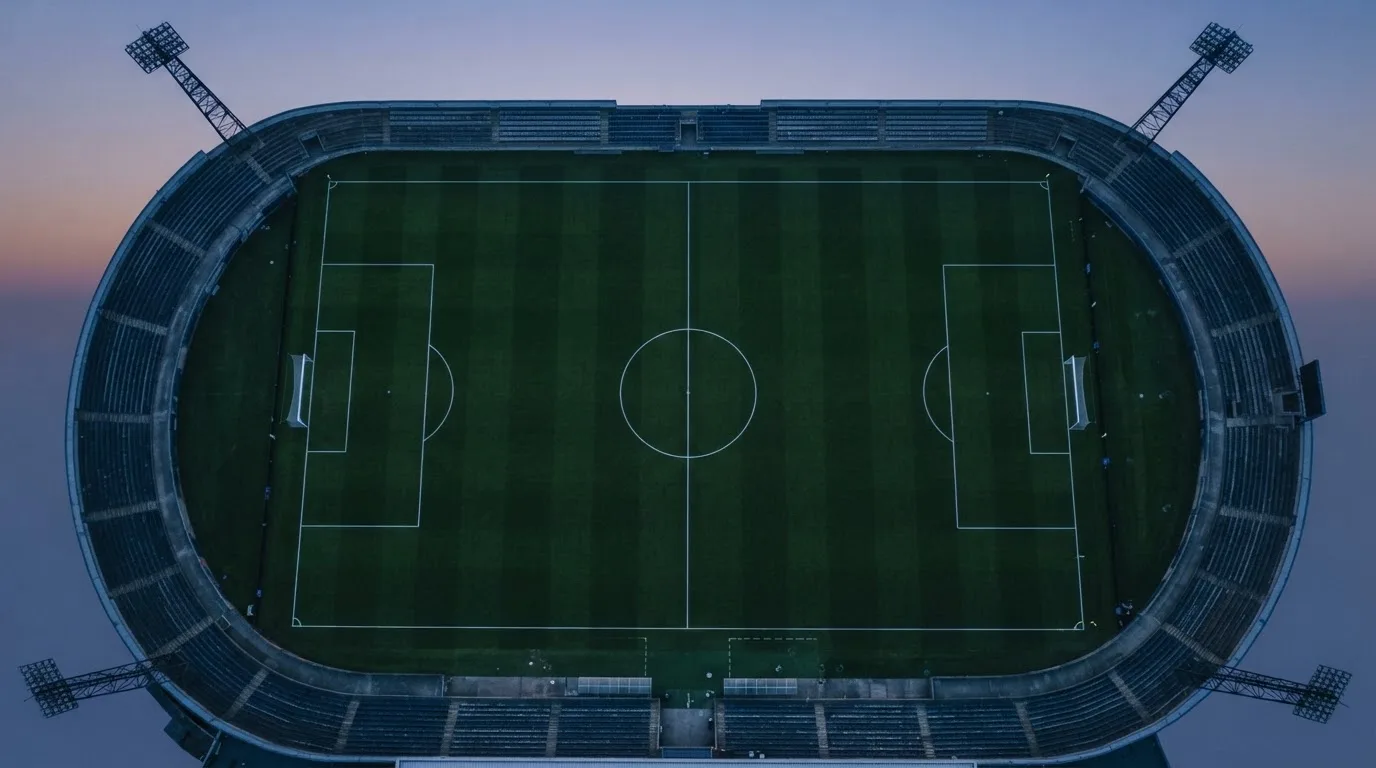 Ein Fußballplatz am Abend aus der Vogelperspektive, Flutlichtmasten ausgeschaltet, die Rasenlinien deutlich sichtbar.