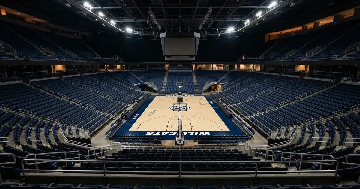 Eine leere Basketballhalle von einer oberen Tribünenreihe aus gesehen, Parkett und Körbe im Licht der Hallenstrahler.
